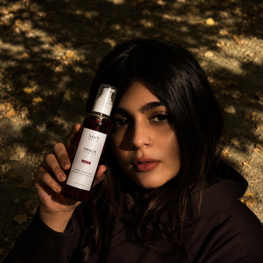 Saach Hibiscus Infused Hair Oil bottle with hibiscus flowers and natural ingredients on a white background.